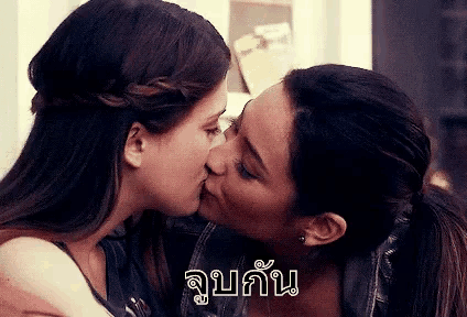 a couple of women kissing each other in a room with a foreign language .