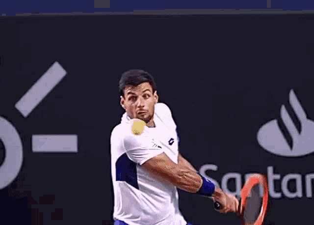 a man in a white shirt and blue shorts is swinging a tennis racket