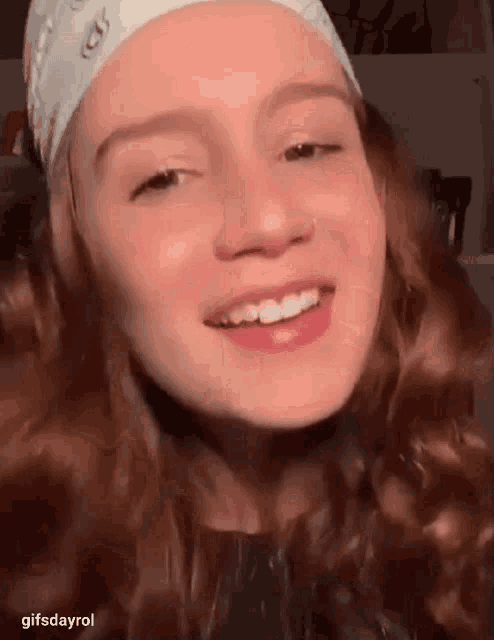 a close up of a young girl wearing a bandana and smiling .
