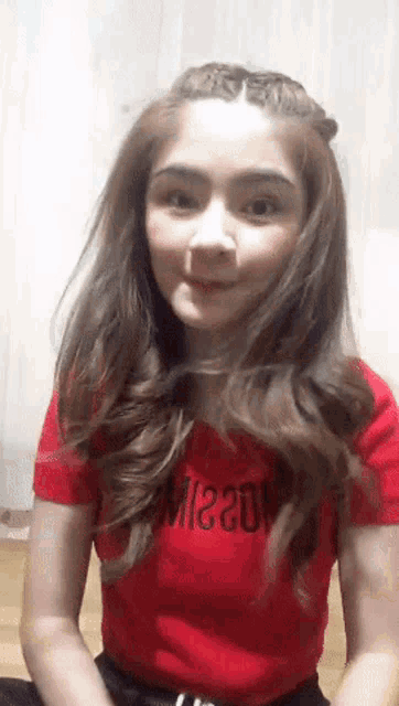 a young girl wearing a red shirt that says ' moschino ' on it