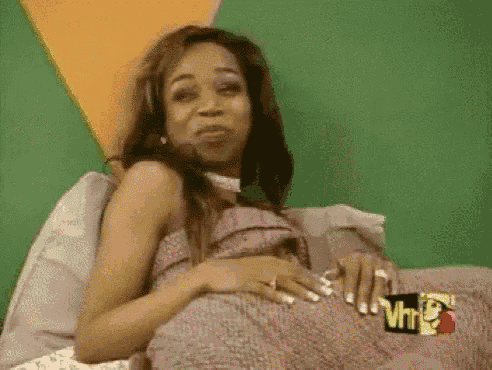 a woman is sitting on a bed wearing headphones and holding a blanket .