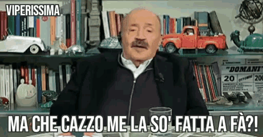 a man with a mustache is sitting at a table in front of a bookshelf with the words viperissima on the bottom right
