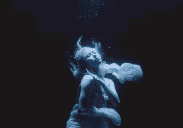 a woman in a white dress is underwater in a dark room