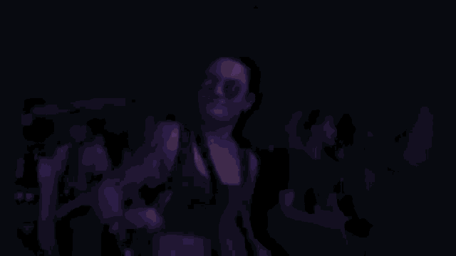 a woman wearing sunglasses stands in a crowd of people with a black tank top that says kard on it
