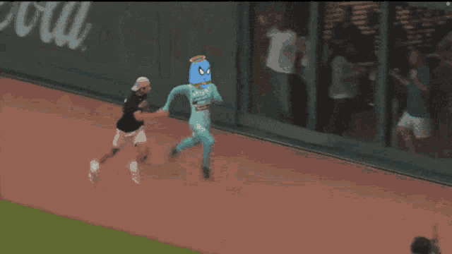 a man in a blue mask is running on a track with a woman behind him