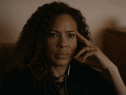 a woman with curly hair and a ring on her finger looks at something