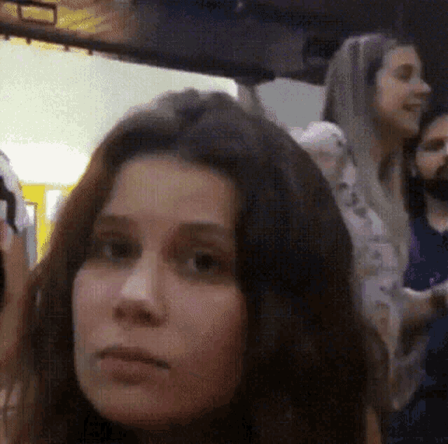 a close up of a woman 's face with a group of people behind her