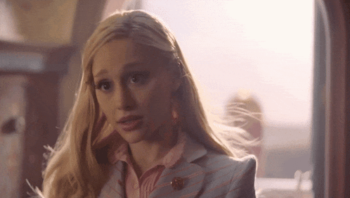 a woman with blonde hair is wearing a striped suit and a pink shirt .