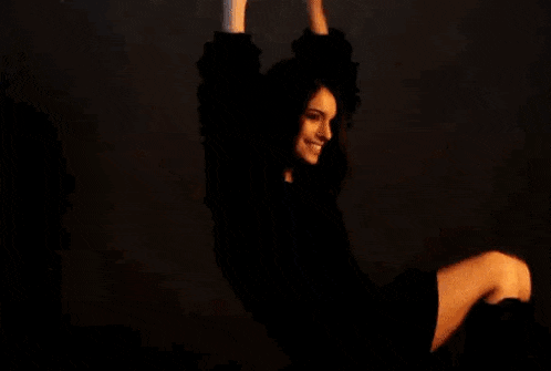 a woman in a furry sweater is sitting on the floor with her arms in the air