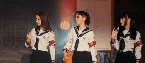 three girls in school uniforms are standing next to each other and dancing .