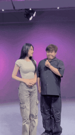 a man and a woman are standing next to each other in front of a purple backdrop
