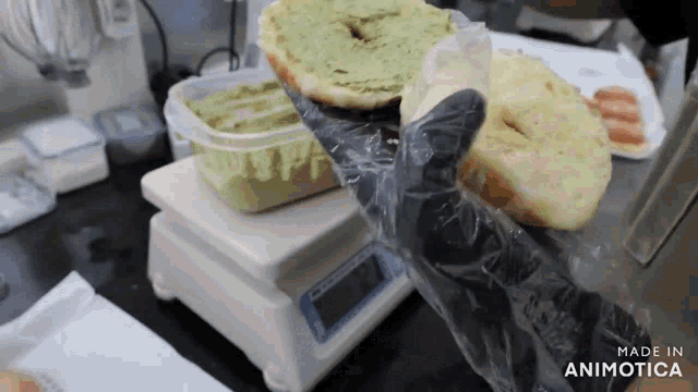 a person wearing black gloves is holding a bag of food on top of a scale that says made in animotica