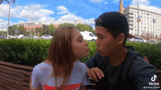 a man and a woman kissing on a bench with tiktok written on the bottom right