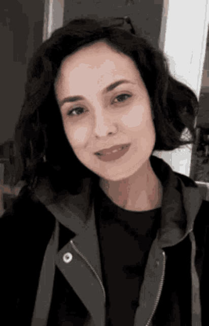 a woman is wearing a black shirt and a gray jacket