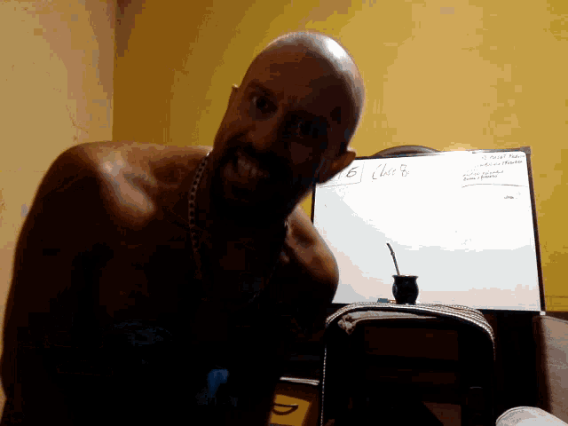 a shirtless man stands in front of a white board that has the number 6 on it