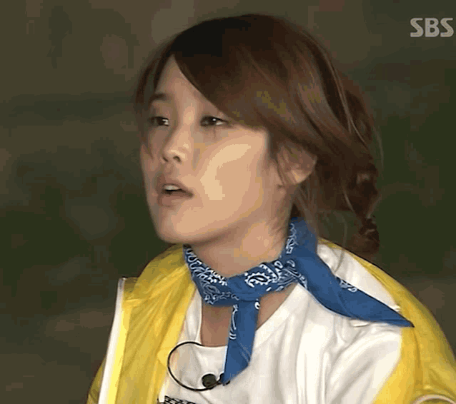 a woman wearing a yellow jacket and a blue bandana with sbs written on the bottom right