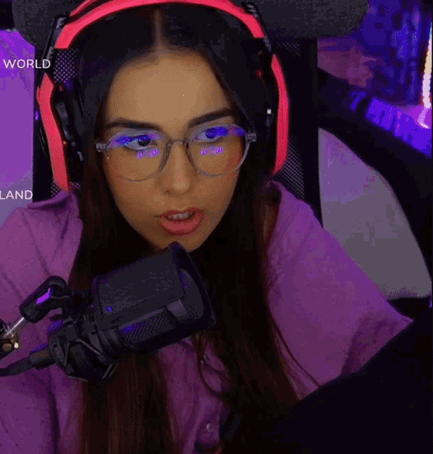 a woman wearing glasses and headphones is sitting in front of a microphone and the word world is on the bottom right