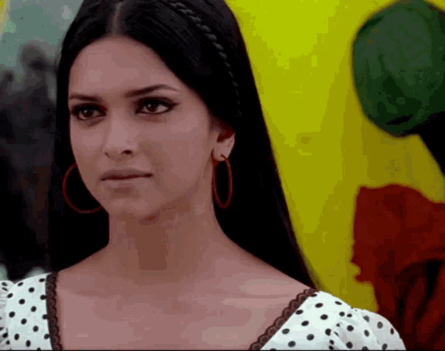 a woman wearing hoop earrings and a white polka dot top