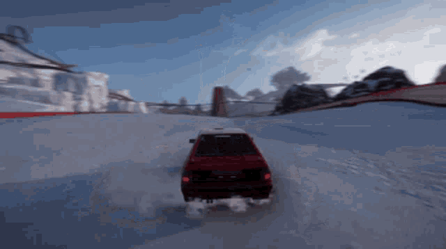 a red car is driving through a snowy area
