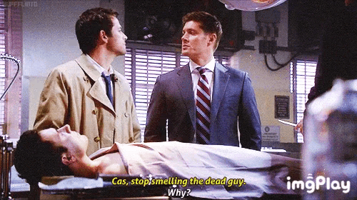 a man in a suit and tie is standing next to a dead body .