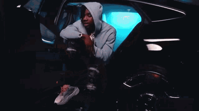 a man wearing headphones stands in front of a black car