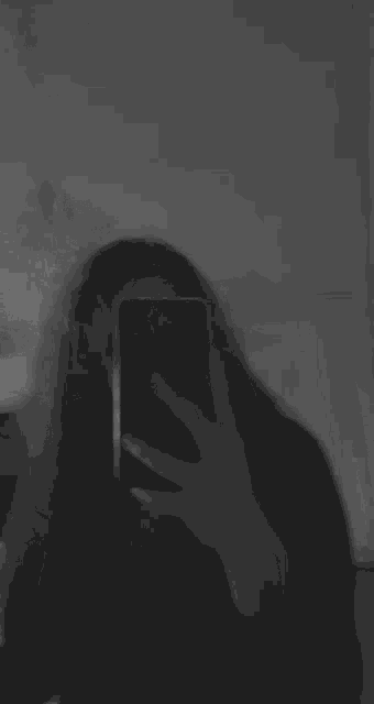 a woman taking a selfie with her phone in a black and white photo