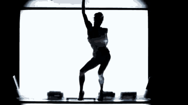a silhouette of a woman dancing in front of a screen