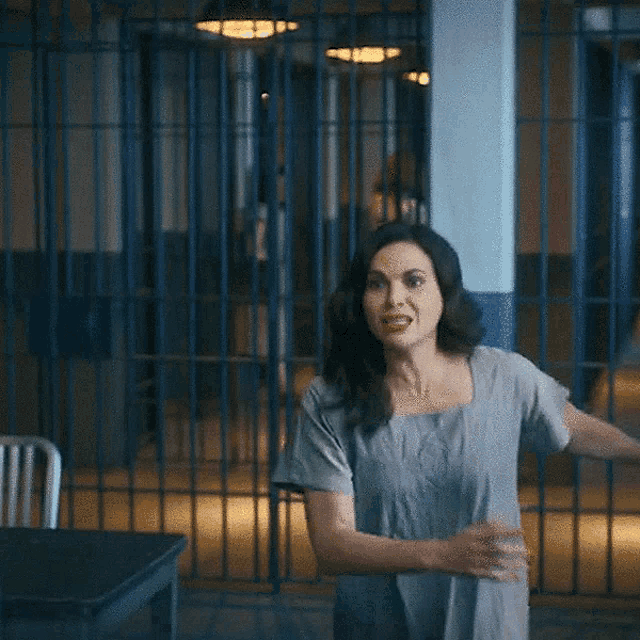 a woman is standing in front of a jail cell looking out a window .