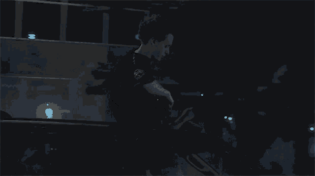 a man in a black shirt is playing a guitar at night