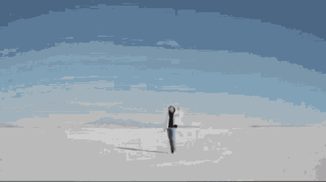 a person wearing a white jacket is walking in the desert