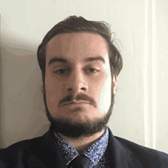 a man with a beard wearing a blue suit and tie