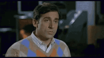 a man wearing a plaid shirt and a sweater is looking at the camera .