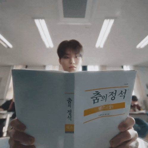 a man is reading a book with korean writing on the cover