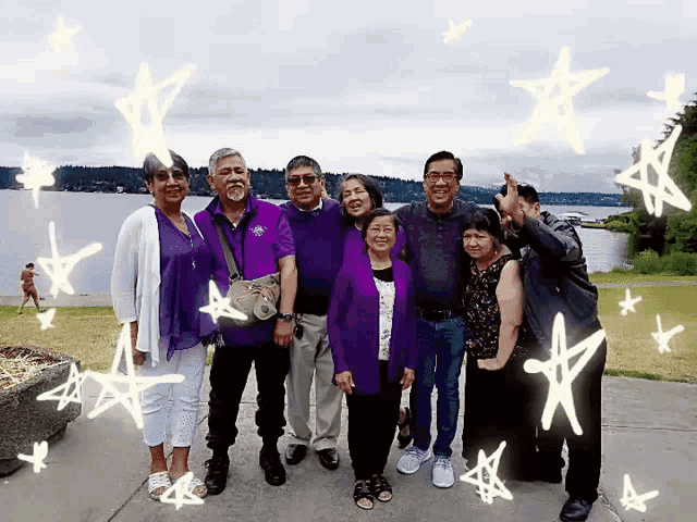 a group of people standing in front of a body of water with stars surrounding them