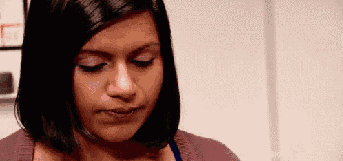 a close up of a woman 's face with a purple sweater and a blue tank top .
