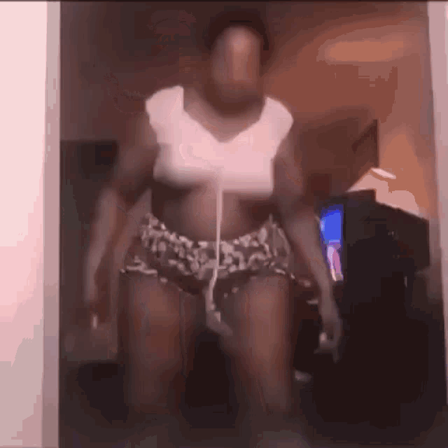 a woman in shorts and a white top is dancing in a room
