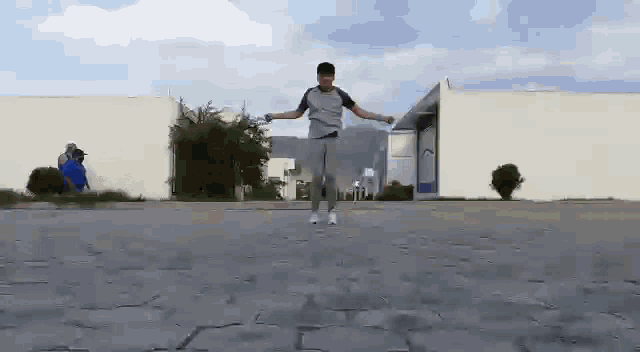 a young man is jumping a jump rope in a parking lot in front of a building .
