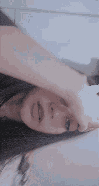 a close up of a woman 's face with her hand on her forehead .