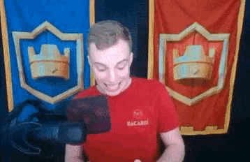 a man wearing a red bacardi shirt is standing in front of two flags .