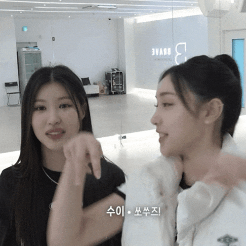 two girls are standing next to each other in a room with a sign that says 3vane on it