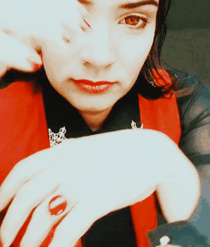 a woman with red nails and a red ring on her left hand