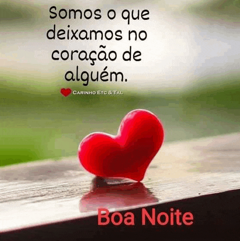 a red heart is sitting on a wooden table with a quote in spanish .