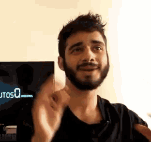 a man with a beard is waving his hand in front of a tv screen that says usosq