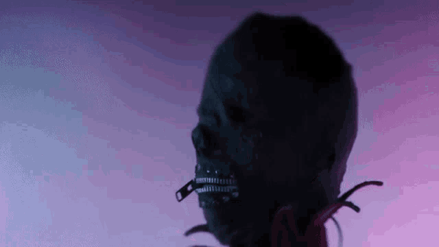 a skull with a zipper in its mouth is standing in the dark .
