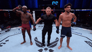 a referee stands between two fighters in a ring with a sign that says ' crypto ' on it