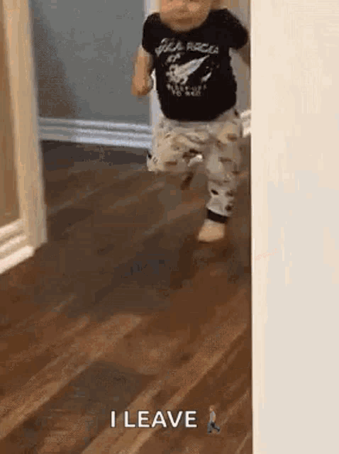 a baby is walking on a wooden floor in a hallway .