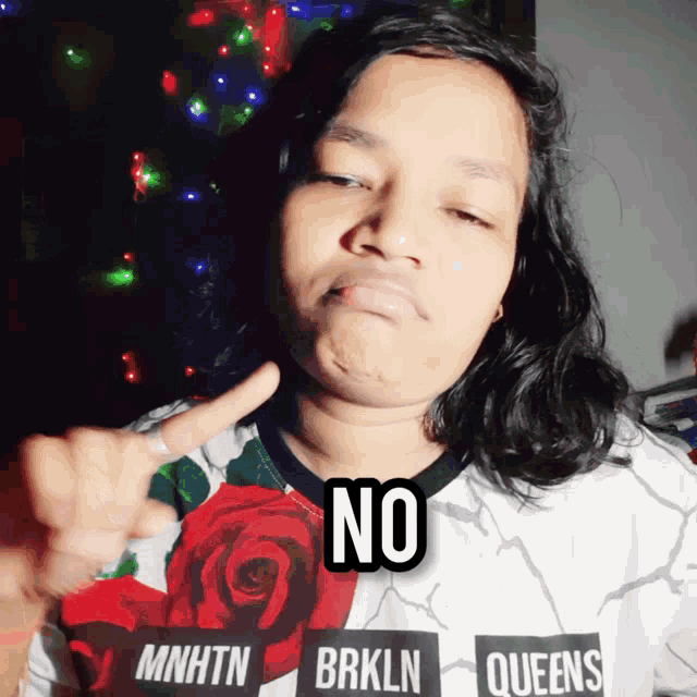 a woman wearing a shirt that says mnhtn brkln queens is making a face