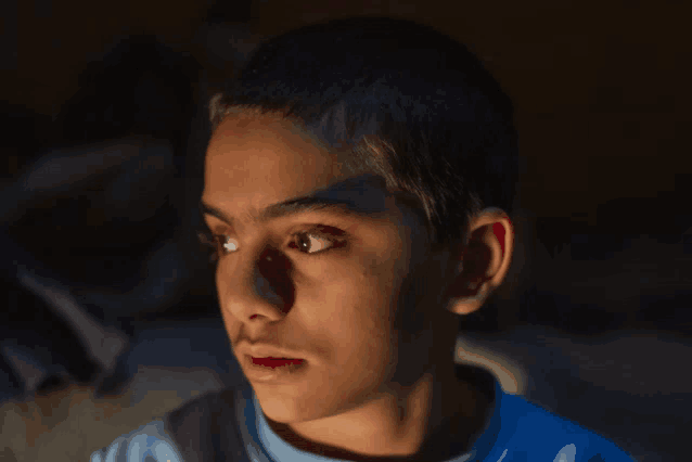 a close up of a young boy 's face in the dark