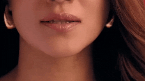 a close up of a woman 's face with her mouth open and lipstick on her lips .