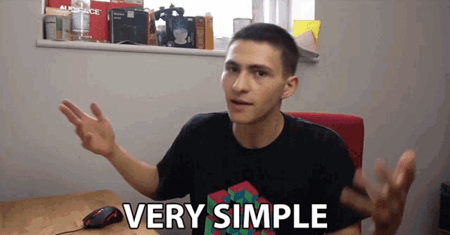 a man sitting at a desk with very simple written on the front of his shirt
